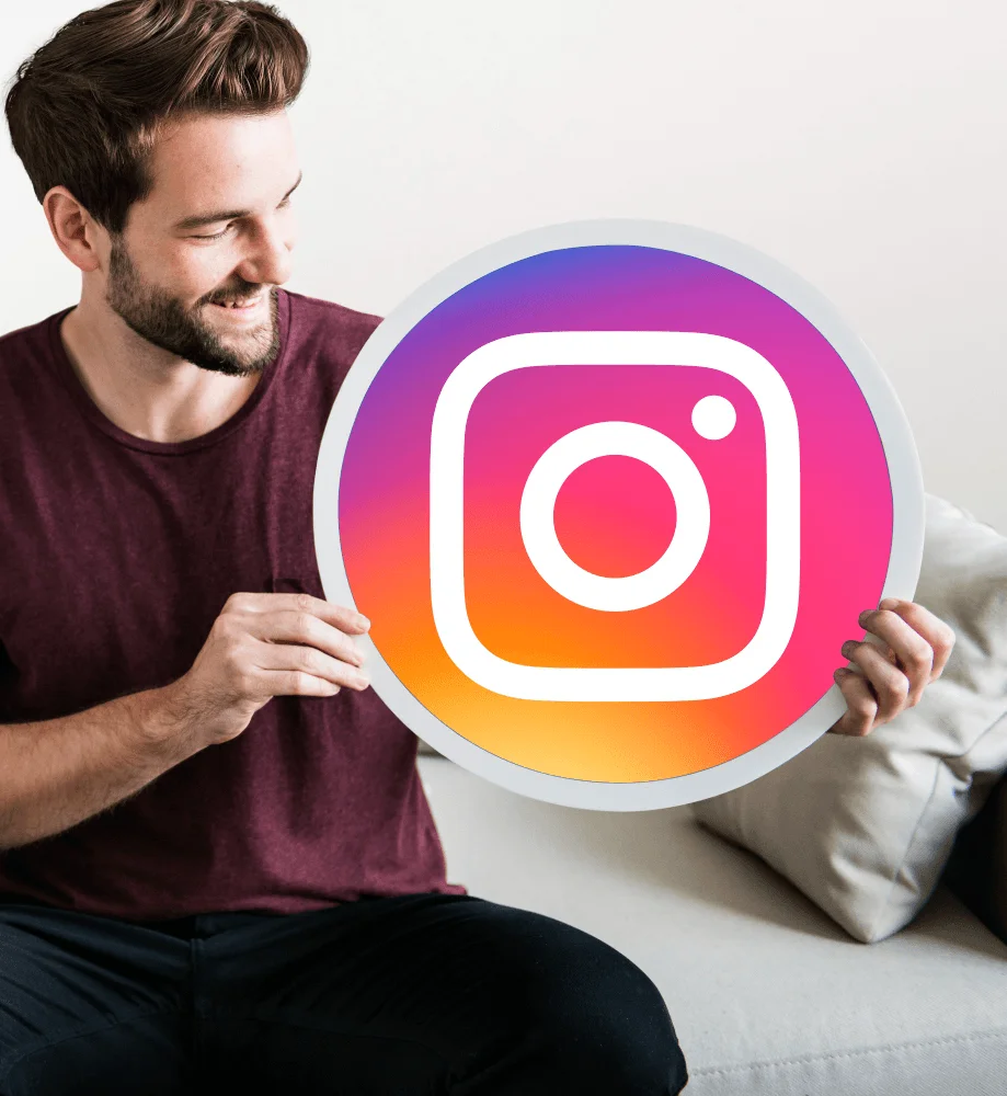 Smiling man holding a large Instagram logo cutout, symbolizing social media engagement.