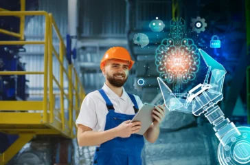 Engineer with a tablet, wearing an orange helmet, standing in an industrial setting with AI robotic arm and digital icons, highlighting engineering applications of artificial intelligence.