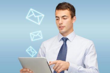 Professional man using a tablet with virtual email icons floating around, symbolizing email marketing jobs.