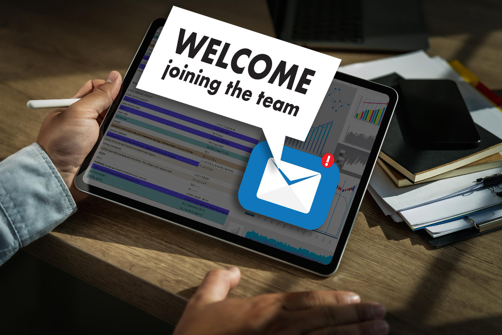 Person holding a tablet with a welcome email notification, signifying new team member onboarding.