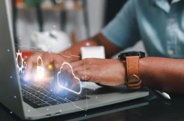 Person working on laptop with hybrid cloud security icons on screen