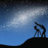 Person stargazing through a telescope under a starry night sky.